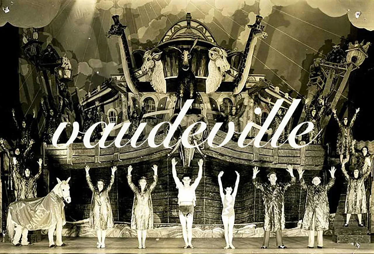 Une photographie ancienne représente une troupe de théâtre en train de jouer sur scène.