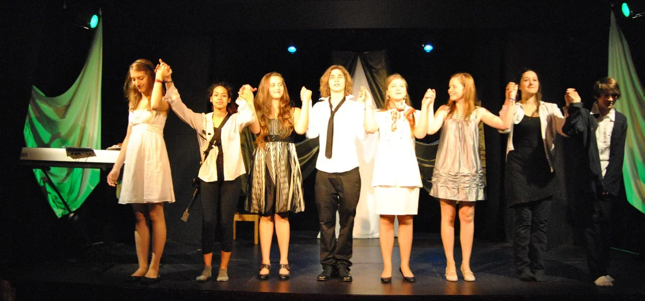 Sur scène, de jeunes comédiens costumés pour la représentation de Molière répètent les derniers saluts.