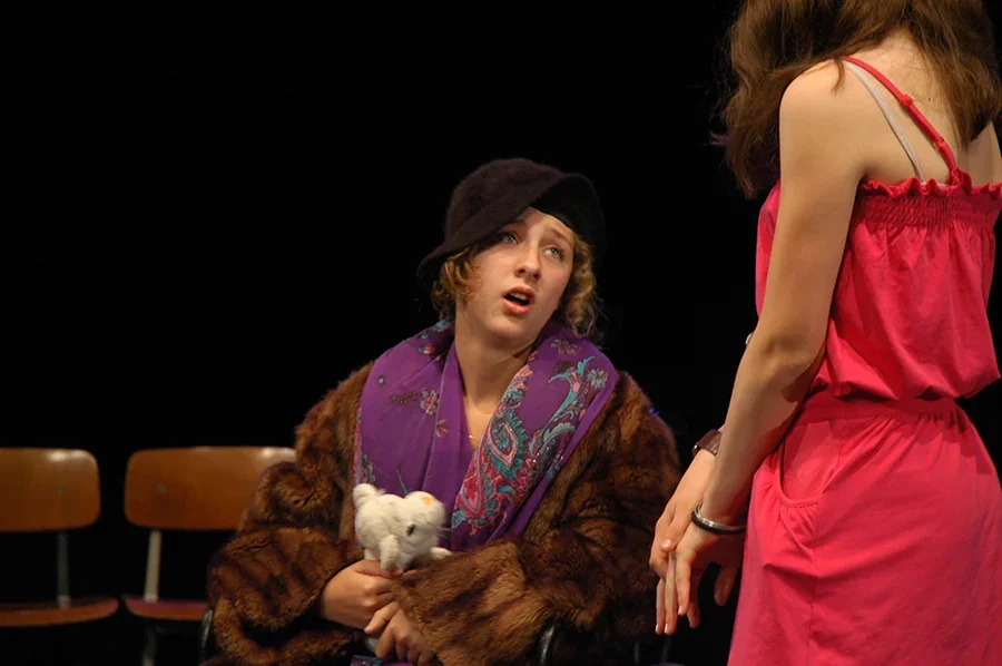 Une adolescente jouant le rôle d'une grand-mère vêtue d'un manteau de fourrure, accompagnée de sa petite-fille, jouent une scène d