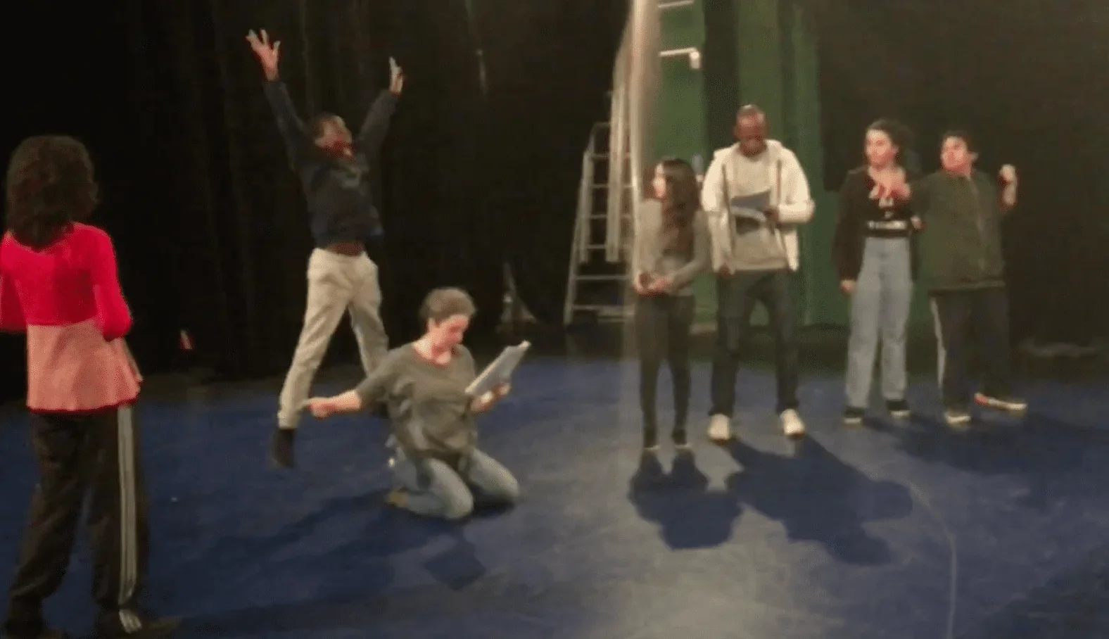 Un groupe d'adolescents passionnés de théâtre présente une scène sur scène lors d'une répétition. Ils sont concentrés et déterminé