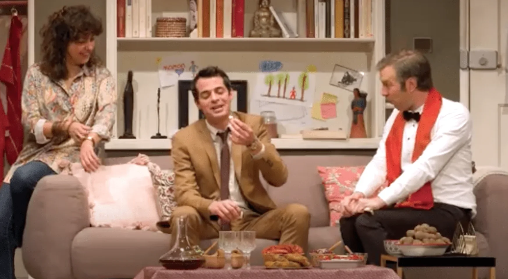 Dans cette photo, nous voyons trois personnages de la pièce de théâtre Le Prénom. Au centre de l'image, nous avons une femme debou