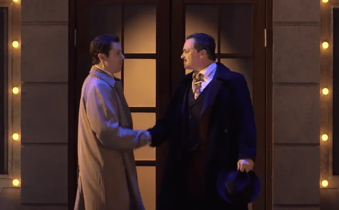 La photo montre les deux héros principaux de la pièce de théâtre "Les Producteurs", Max et Léon, en train de se tenir les mains su