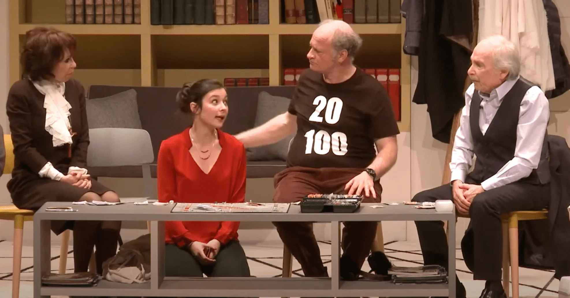 Sur scène, une jeune fille explique quelque chose aux autres patients, tous l'écoutant attentivement. Son visage est sérieux et dé