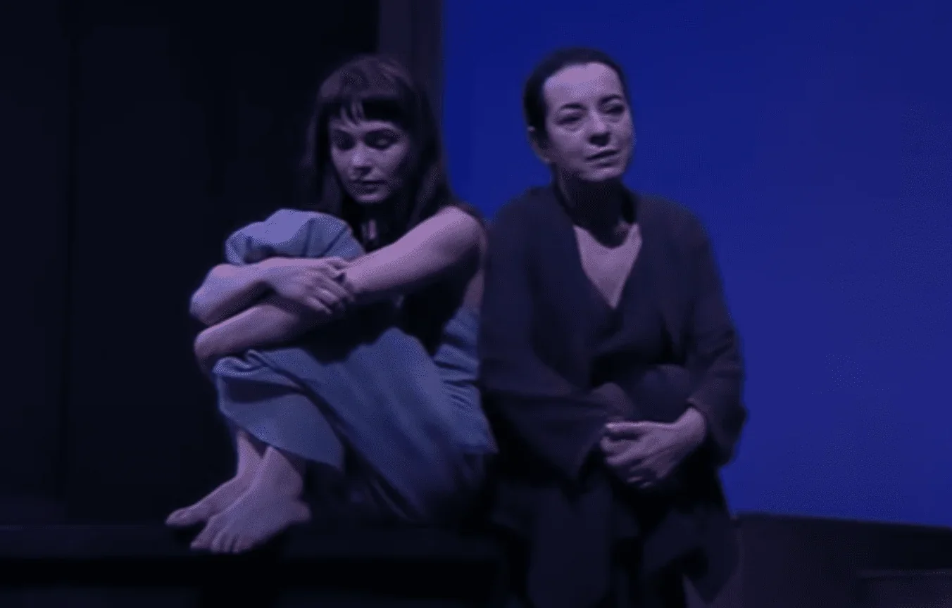 Les deux femmes se tiennent debout, chacune en train de regarder dans une direction différente, illustrant la tension et la distan