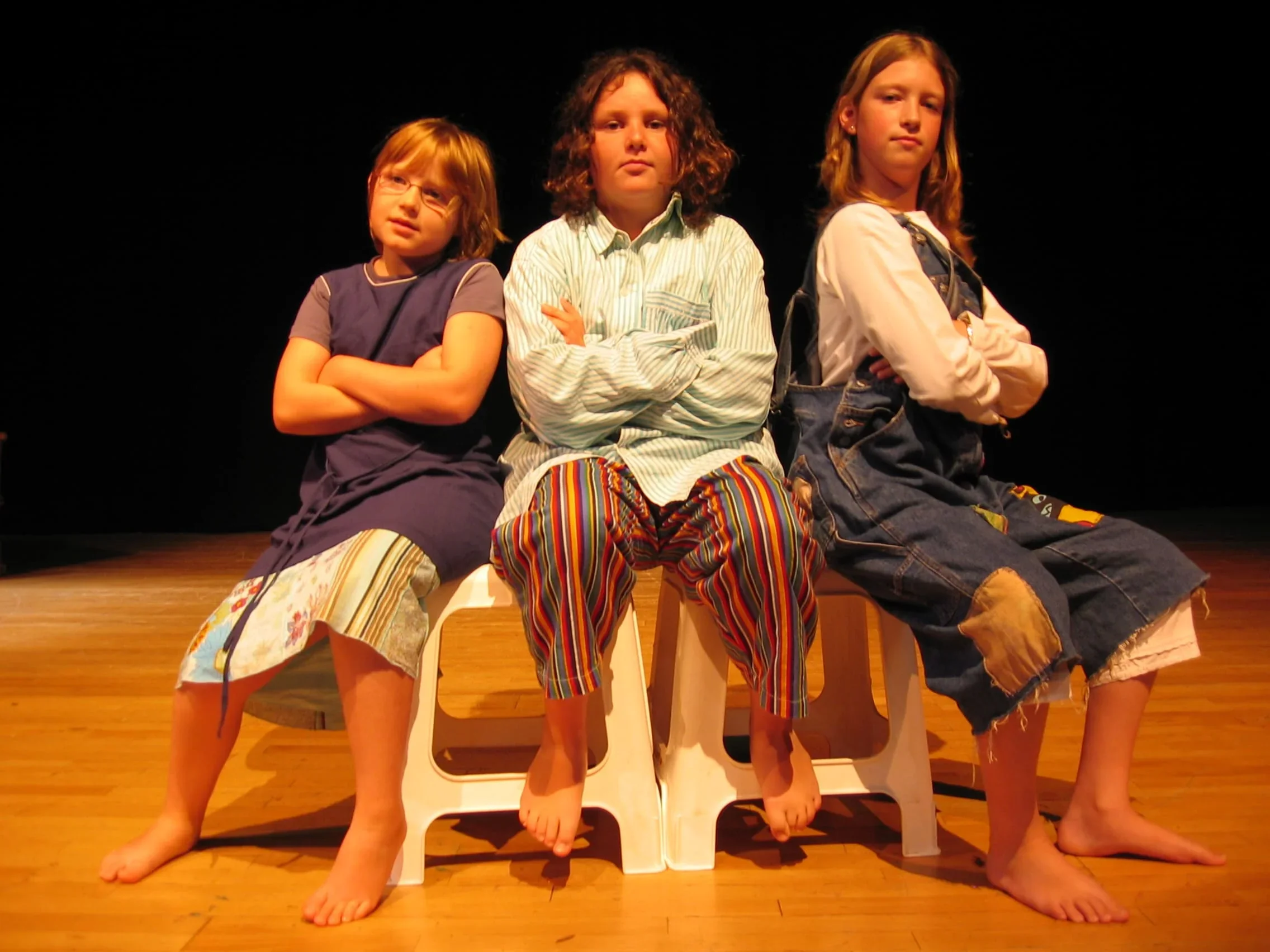 Cette photo captivante montre trois filles assises sur des tabourets, proposant une scénette remplie d'émotions. Leur talent et le