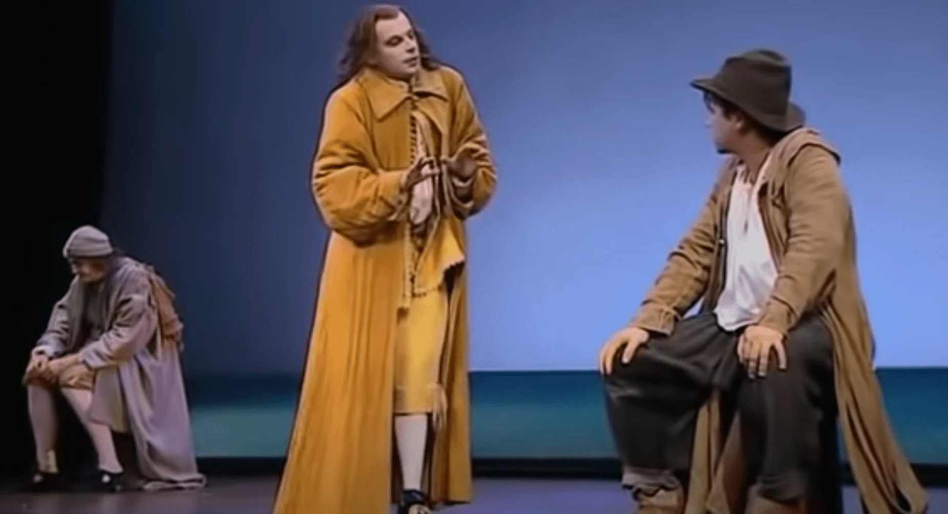 Dans cette image saisissante, nous sommes transportés au cœur d'une représentation théâtrale inoubliable. Sur scène, trois comédie