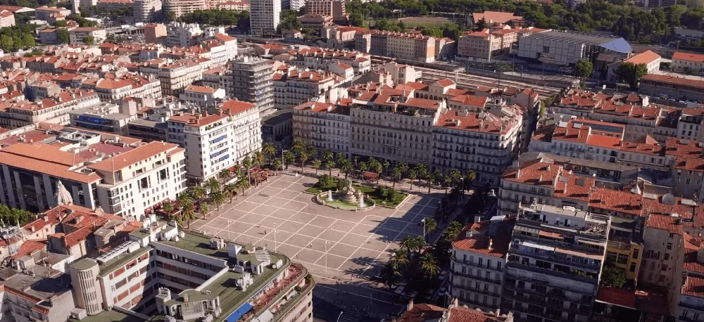 Cette photographie offre une vue aérienne saisissante de la ville, où les toits rouges des bâtiments créent une scène colorée et v