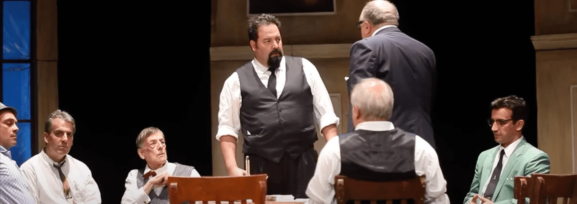 L'image saisissante présente une scène dynamique du spectacle "12 hommes en colère" où les douze jurés sont assis autour d'une tab