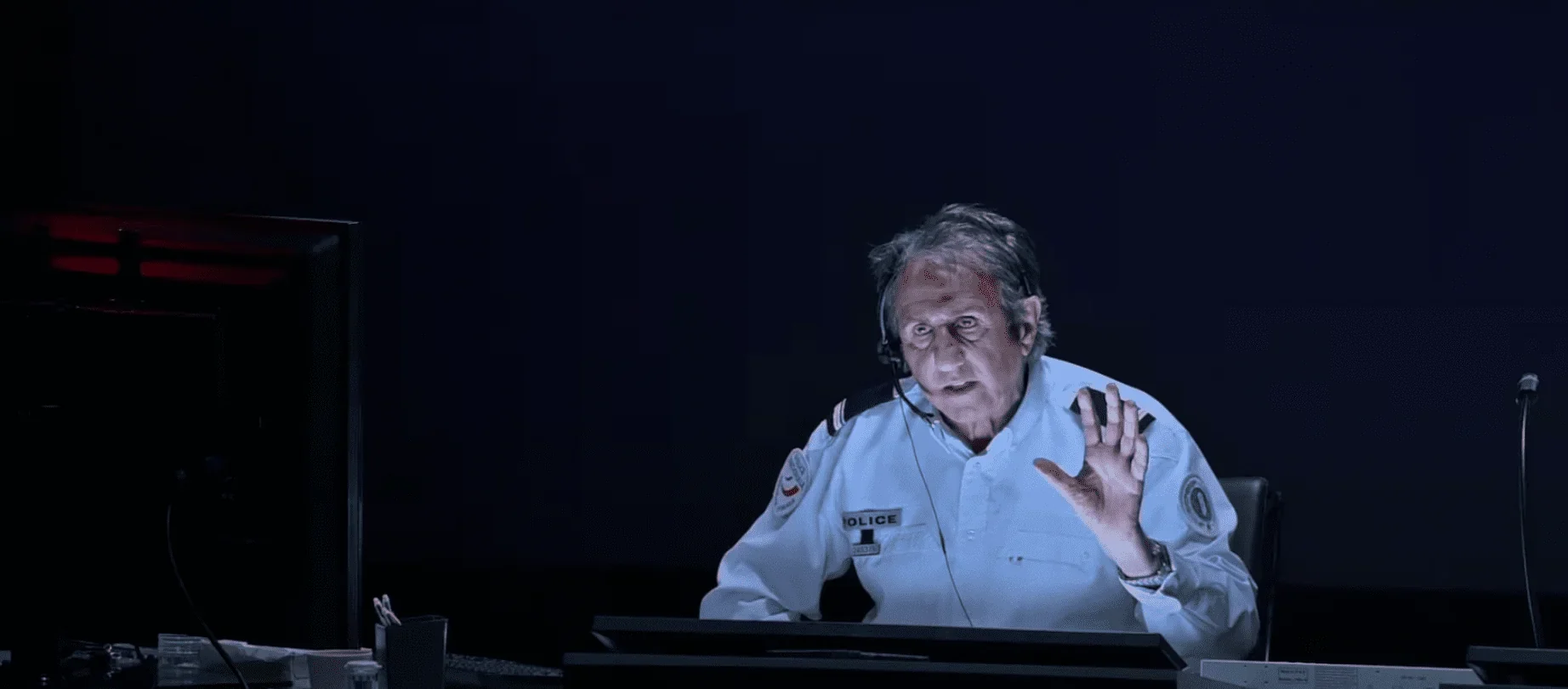 Dans cette photo captivante, nous voyons un policier se tenant devant un panneau de contrôle des appels.