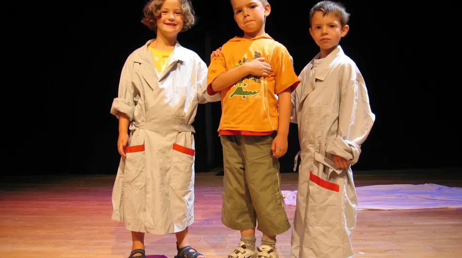 Cette photo captivante nous montre trois petits comédiens en train de se préparer pour une improvisation sur scène. Leur concentra